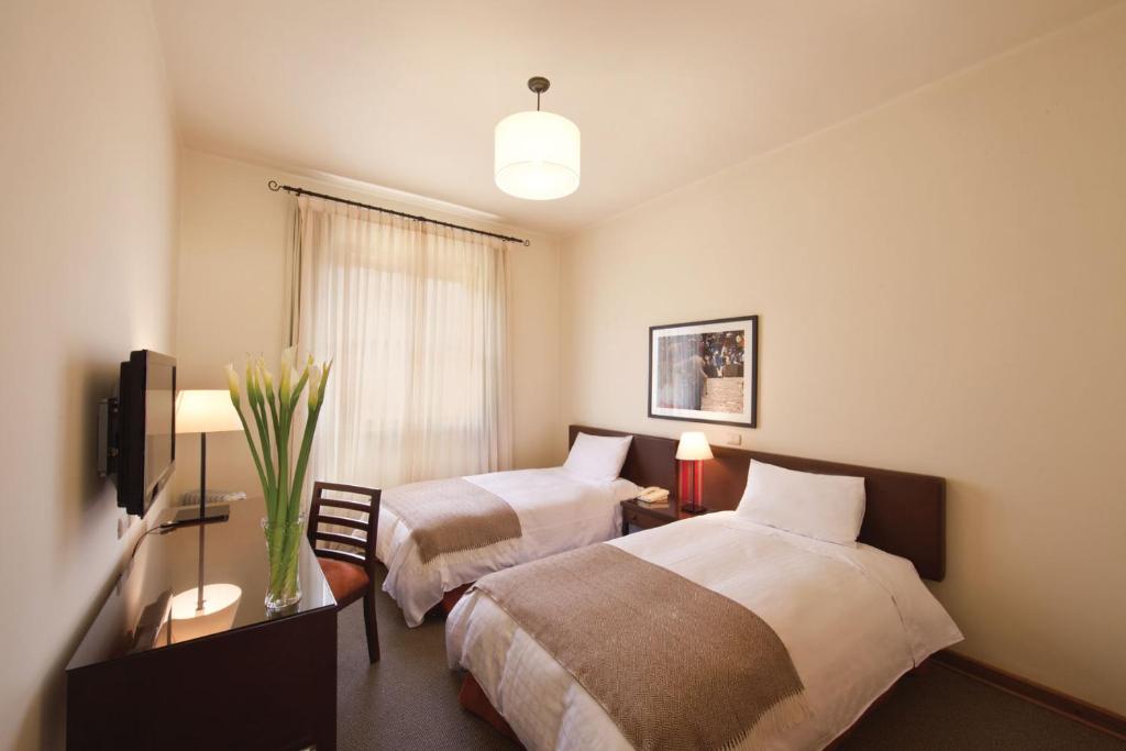 塔尔马LP Los Portales Hotel Tarma的酒店客房设有两张床和电视。