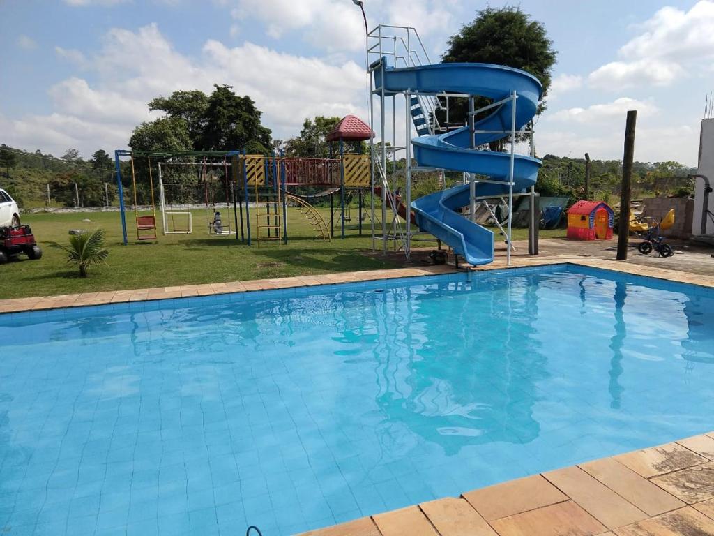 科蒂亚Chácara 4 Ases J R的公园里一个带蓝色滑梯的大型游泳池