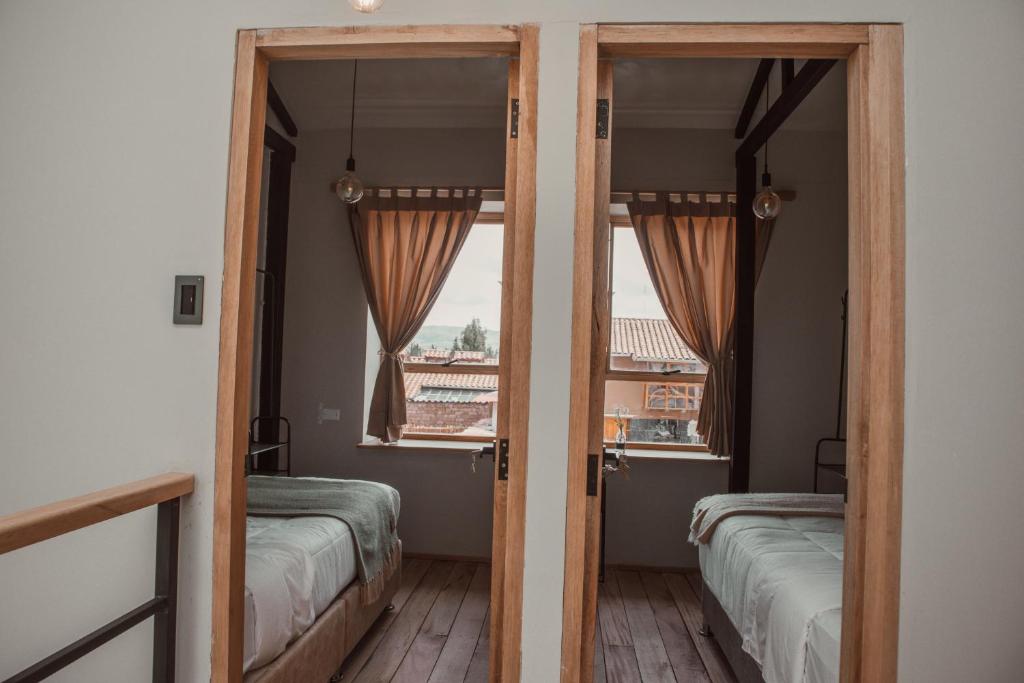 库斯科Casa Faustina - Templo de la Luna的客房设有两张床和窗户。