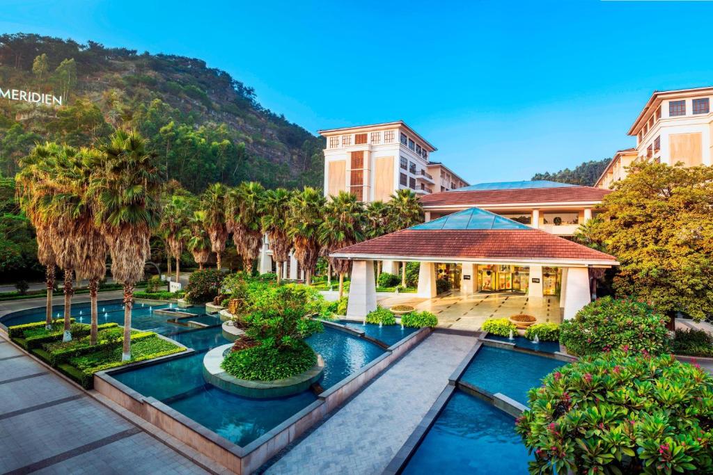 厦门厦门艾美酒店（位于城市公园之中，森林氧吧）的一座带游泳池、棕榈树和大楼的度假村