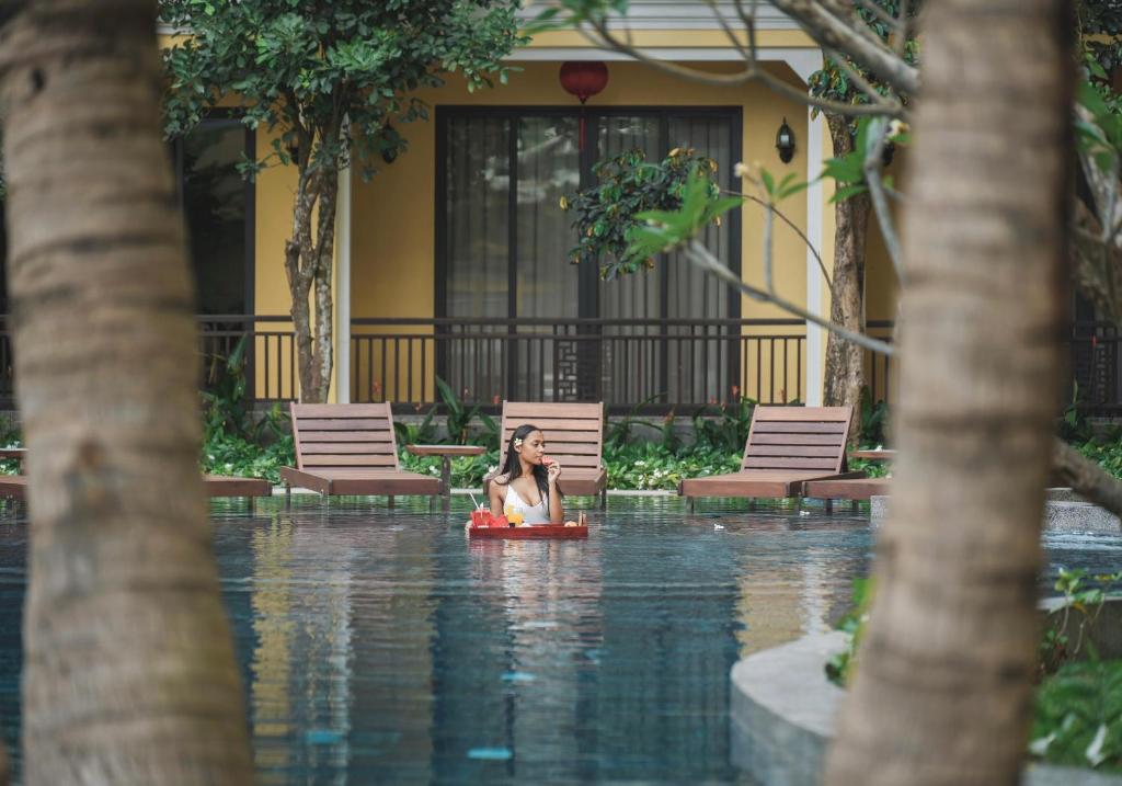 会安Ahoy Hoi An Boutique Resort & Spa的坐在排筏上水塘里的女人