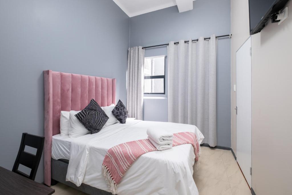 开普敦Cape palm royal guest house的一间卧室配有一张带粉红色床头板的大床