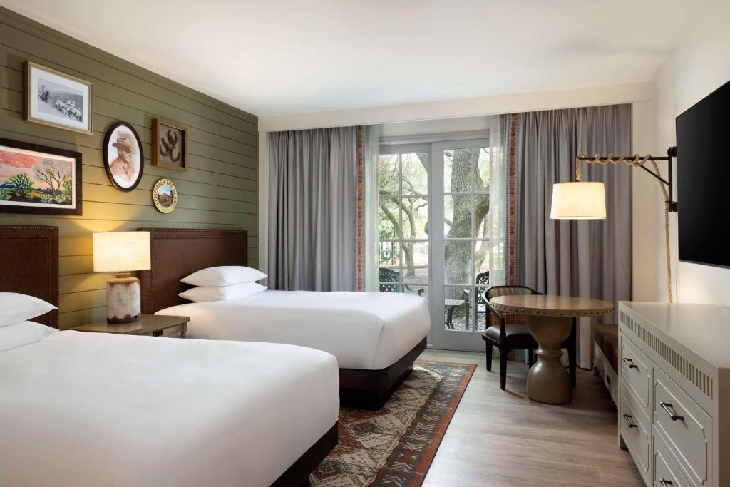 圣安东尼奥凯悦山乡村度假酒店及Spa中心的酒店客房设有两张床和一张桌子。