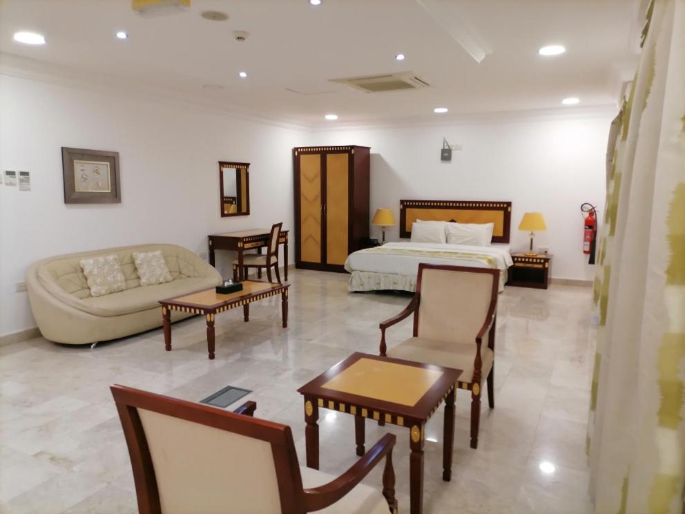 马斯喀特马斯喀特先锋公寓酒店的酒店客房配有一张床、一张沙发和椅子。