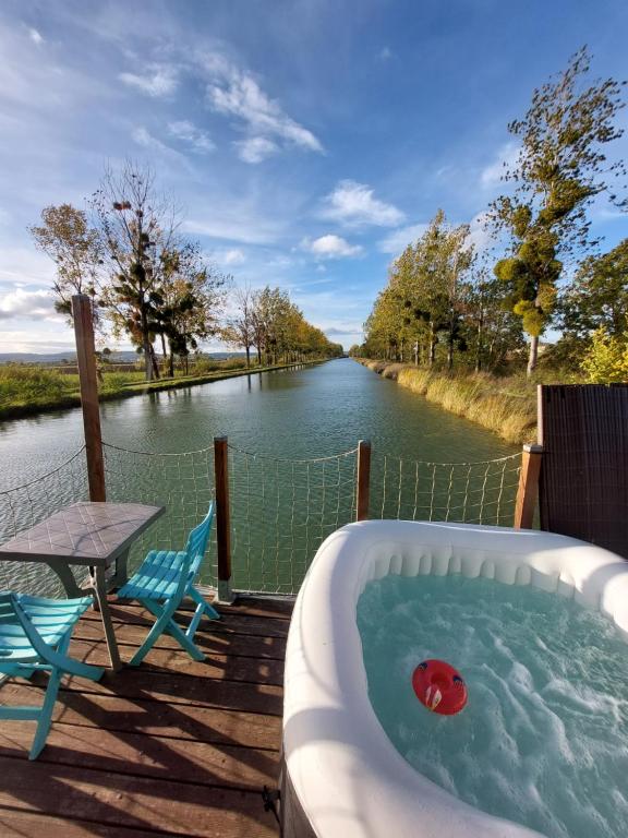 Cottage flottant terrasse jacuzzi option aux Portes de Dijon的浴缸位于河边的甲板上