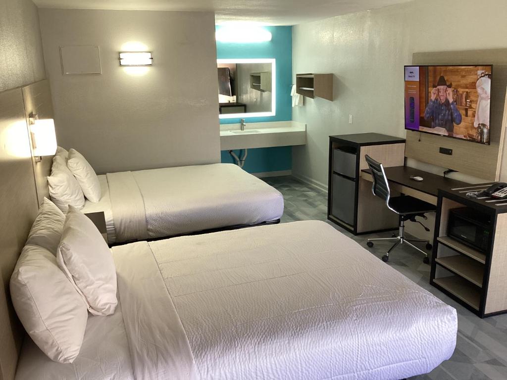 普莱森顿Pleasanton Executive Inn的酒店客房配有两张床和一张书桌