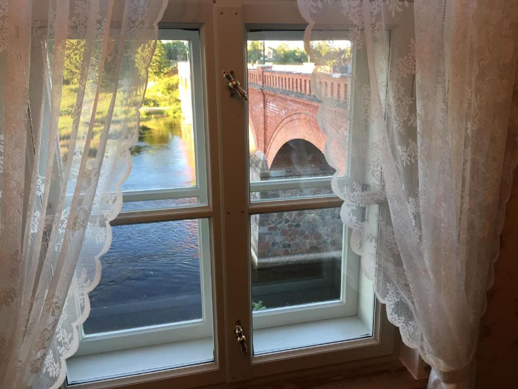 库尔迪加Apartamenti Kuldīgas Pilsdzirnavas的窗户配有白色窗帘,享有桥梁的景致