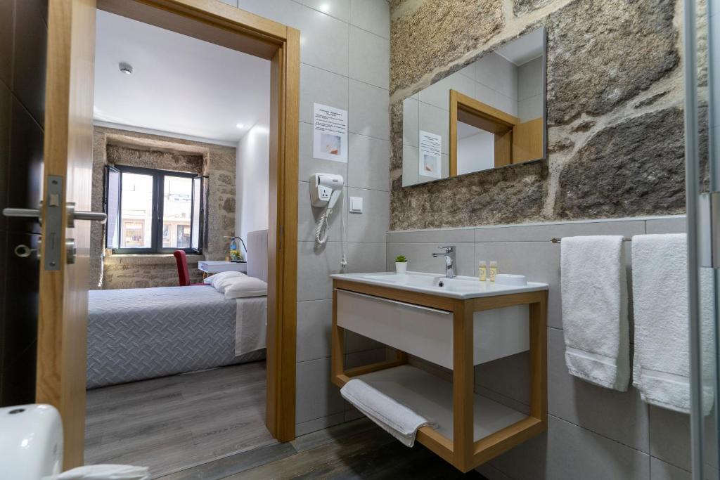 布朗库堡Alojamento Girassol的一间带水槽的浴室和一张位于客房内的床