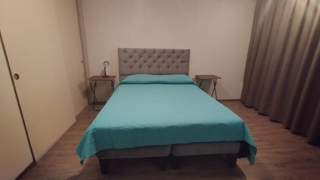 圣地亚哥Alojamiento frente a Turbus的一间卧室配有一张带蓝色毯子的大床