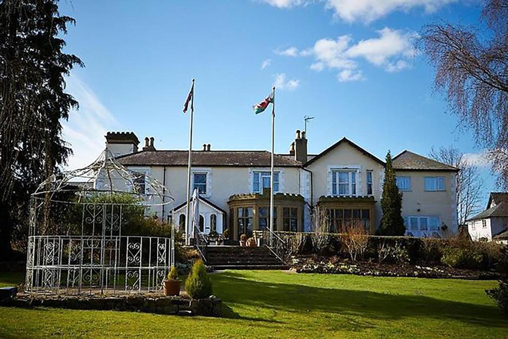 莫尔德Northop Hall Country House Hotel的院子内有两面旗帜的大型白色房屋