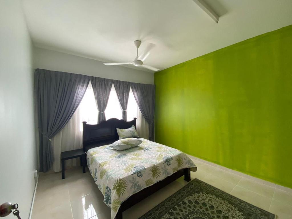 瓜拉丁加奴ALEENA STAYCATION @ APARTMENT TOK PELAM PANTAI BATU BURUK的绿色卧室设有床和窗户