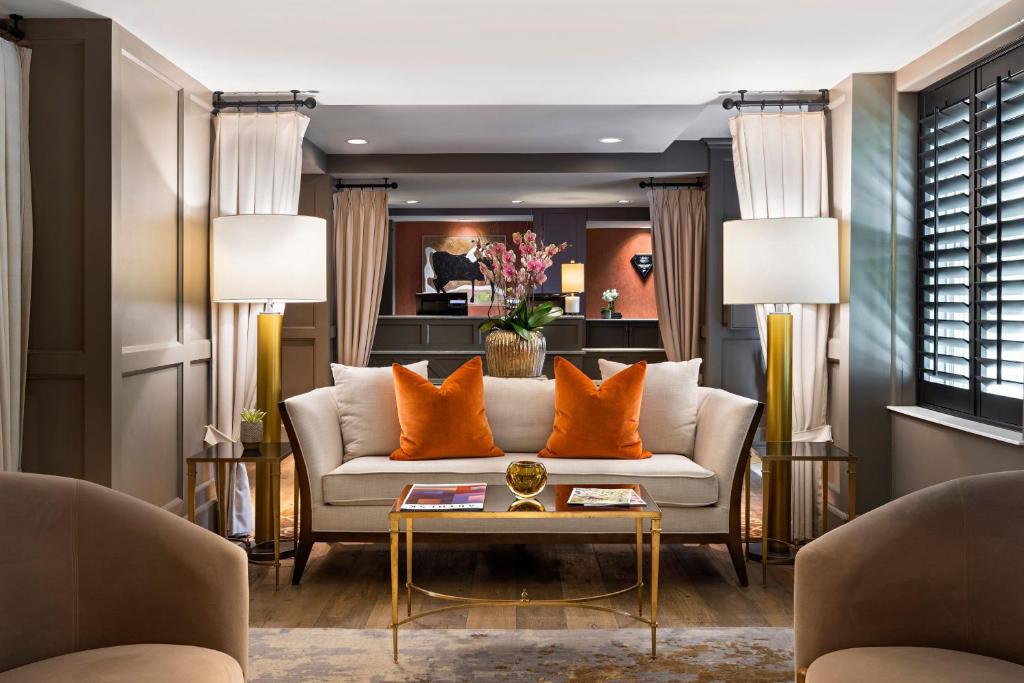 俄克拉何马城傲途格精选酒店系列之俄克拉荷马市大使酒店的客厅配有白色沙发和橙色枕头。