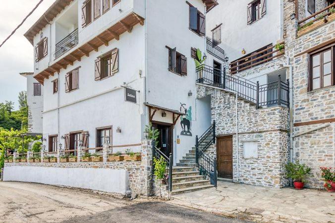 马克里尼撒Makrinitsa Village的一座白色的大建筑,设有楼梯和门