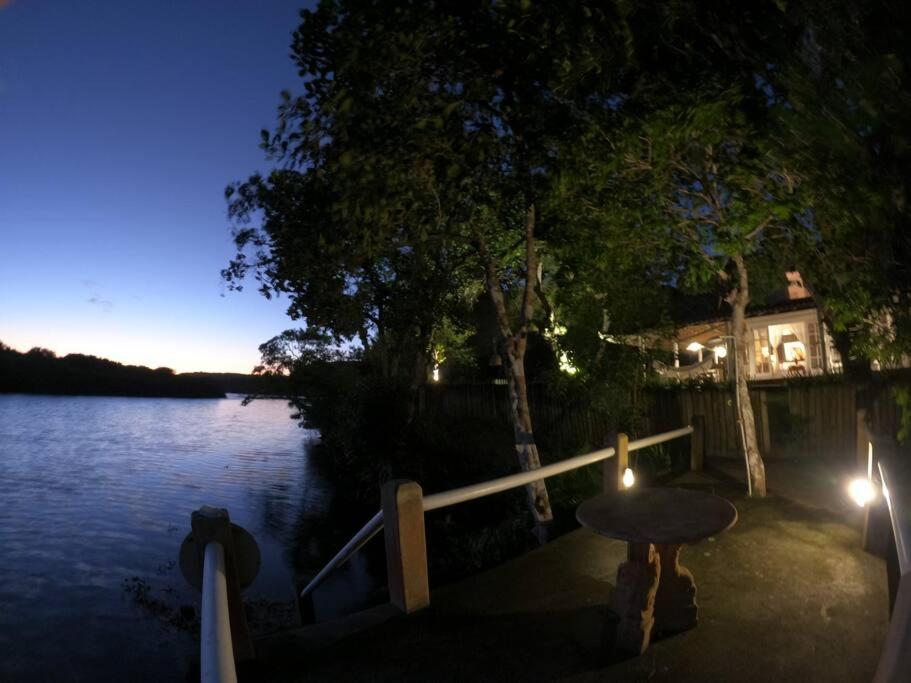 塞古罗港Nature Stay的一张桌子,坐在一排水边,晚上