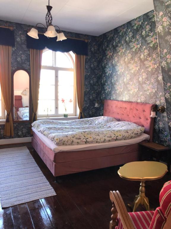 内克瑟Cafebrumman的卧室配有一张床铺,位于带花卉壁纸的房间