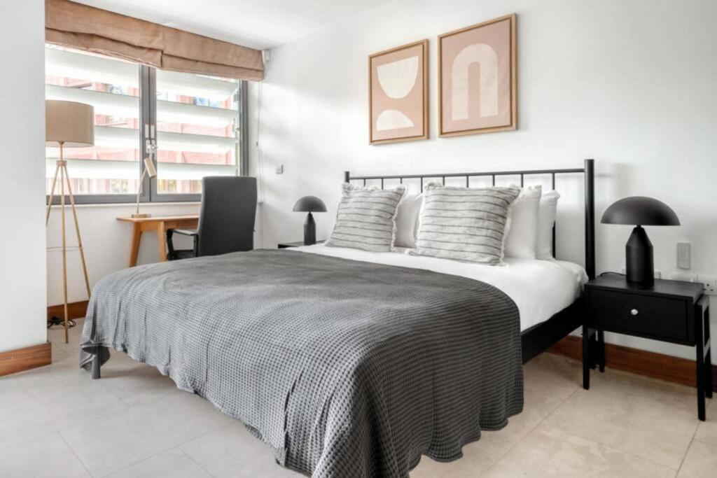 伦敦Exquisite 2 Bed Soho Central Apartment Sleeps 6的一间卧室配有一张带桌子和椅子的床