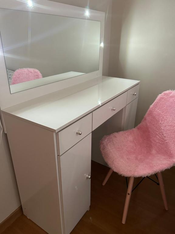 乌贝兰迪亚Apartamento ACOMODA 5 PESSOAS próximo ao Uberlândia Shopping的一张带镜子的白色书桌和一张粉红色椅子