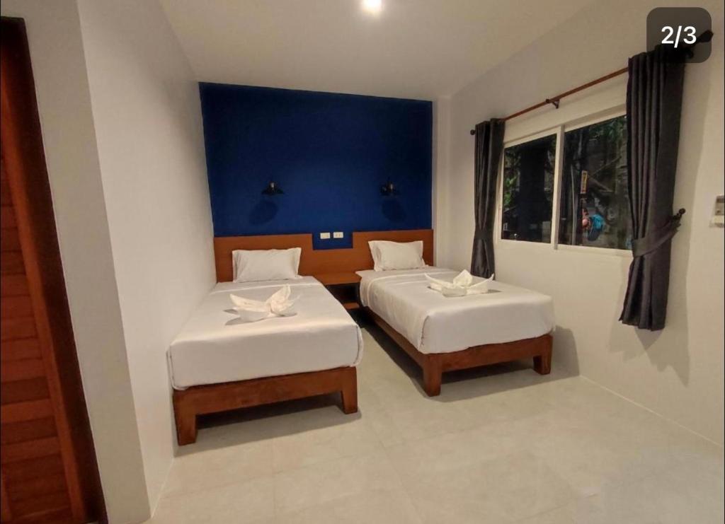 皮皮岛PP. Valentine Bungalow的一间卧室设有两张床和蓝色的墙壁
