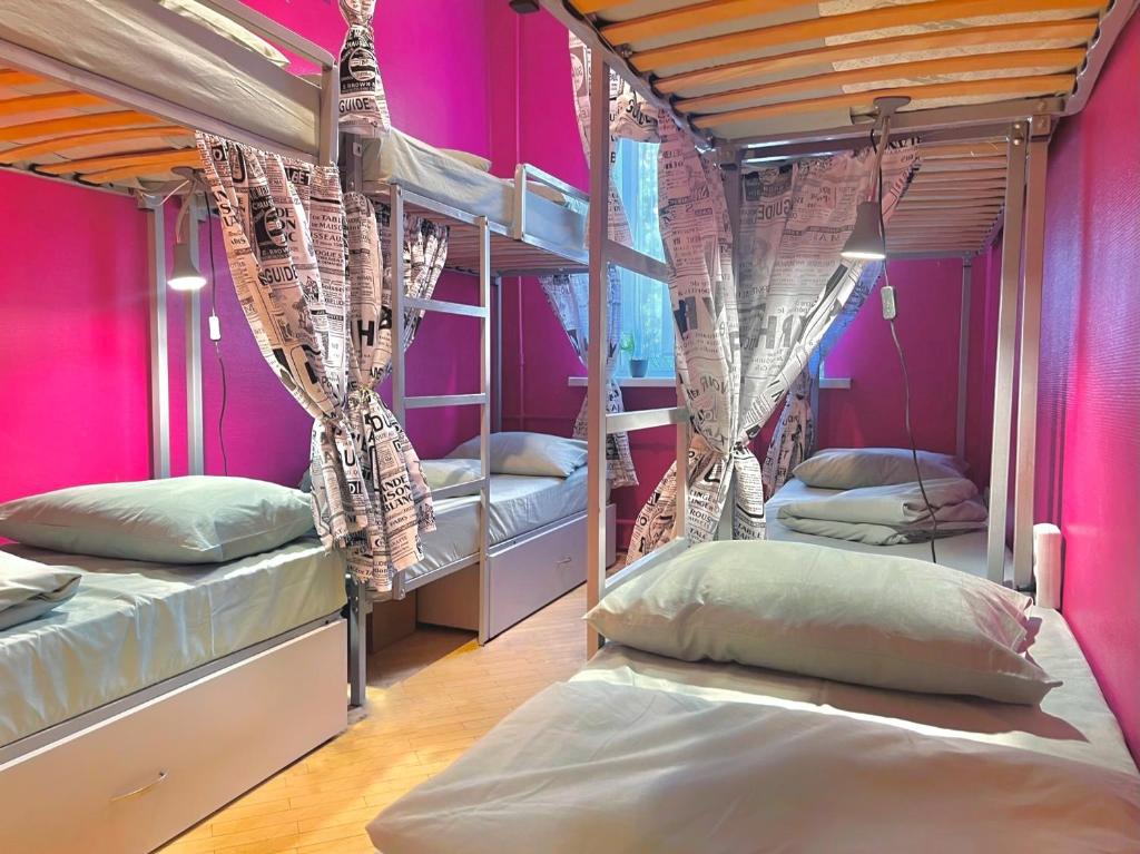 基辅Pechersky Hostel的一间设有三张双层床和粉红色墙壁的客房