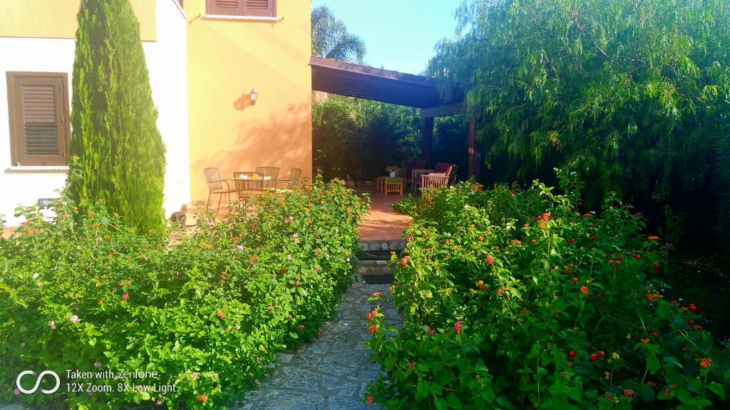卡斯泰拉马莱ViViHolidays的一座花园,里面设有一座房子,还种植了一些灌木和鲜花