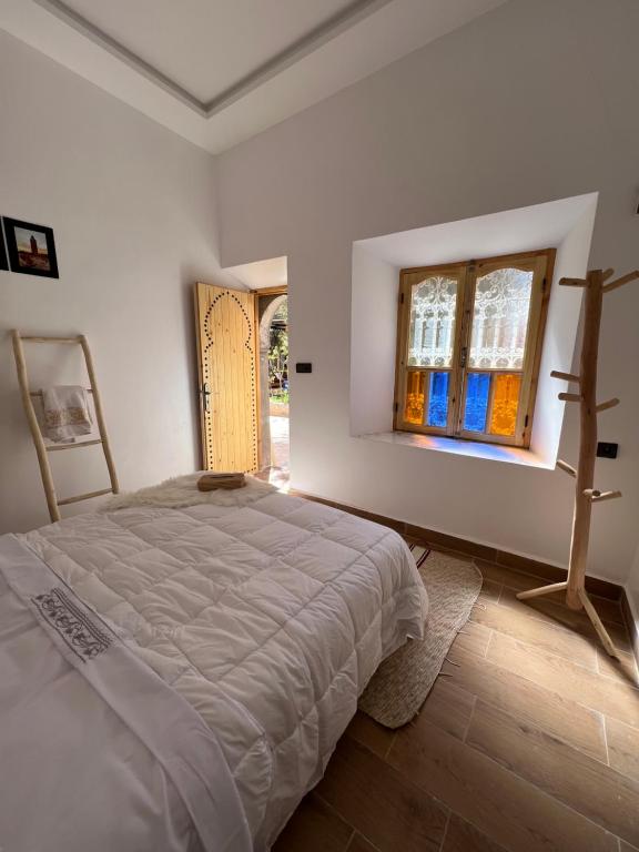 Friendly Dades Lodge的白色的卧室设有床和窗户
