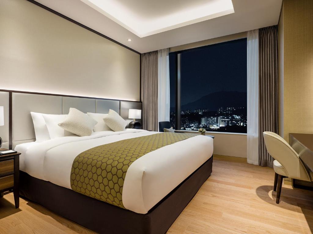 首尔Grand Mercure Ambassador Hotel and Residences Seoul Yongsan的一间卧室设有一张大床和一个大窗户