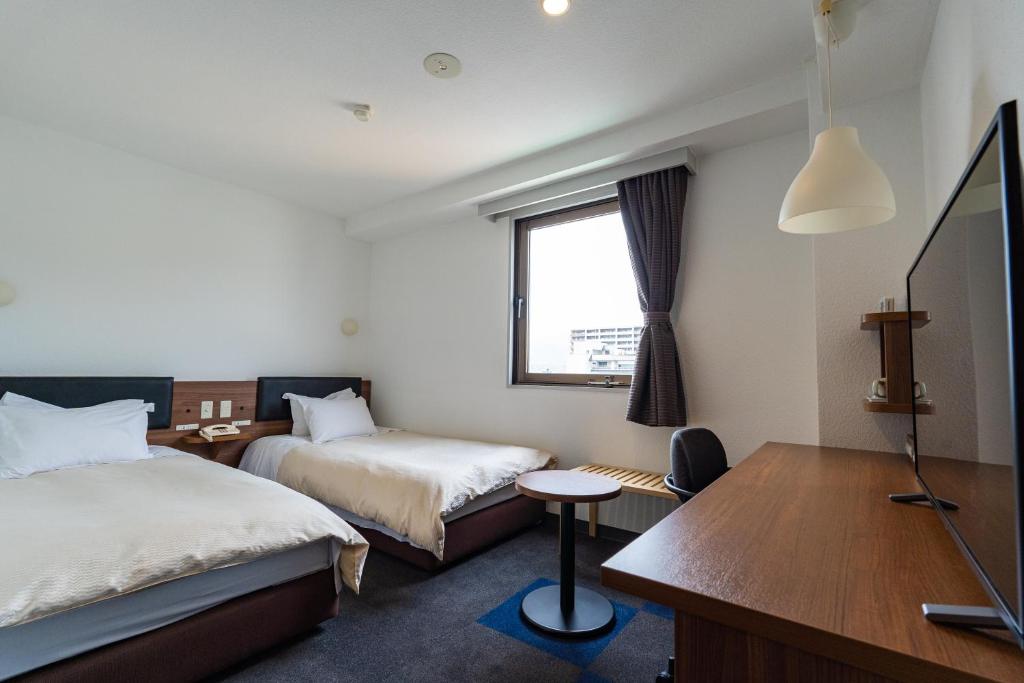 山口Business Hotel Ueno的酒店客房配有两张床和一张书桌