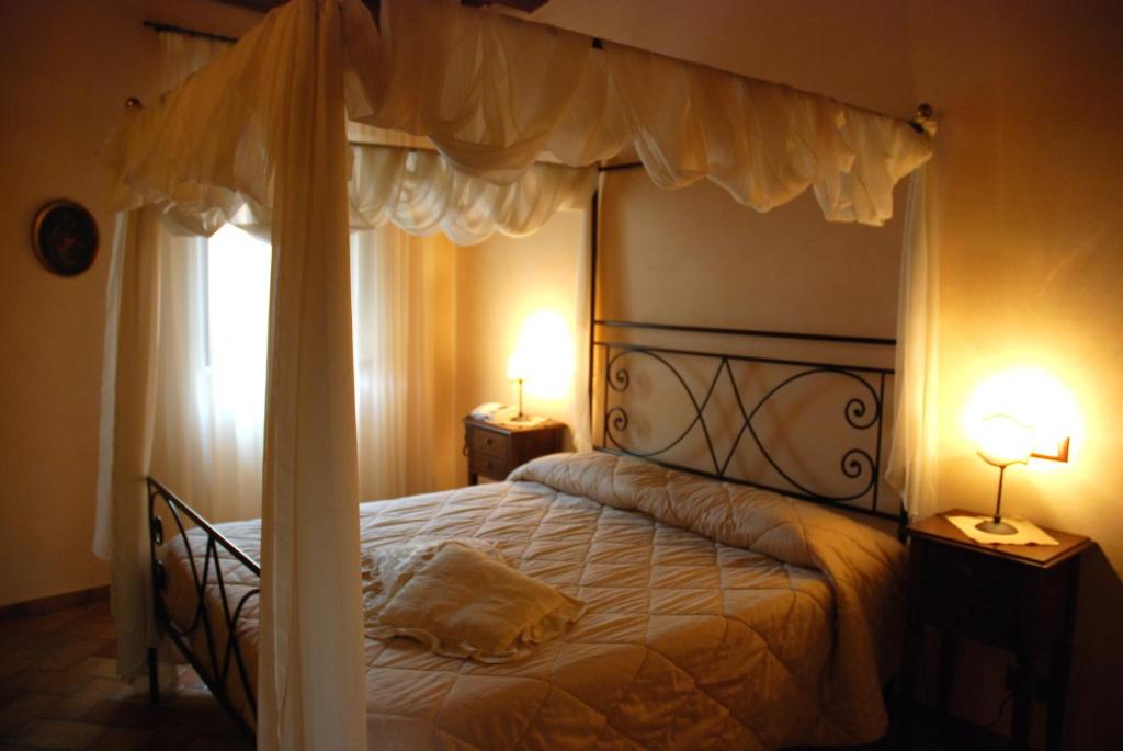 Urbisaglia罗卡达小屋酒店 的一间卧室配有一张带两盏灯的天蓬床。