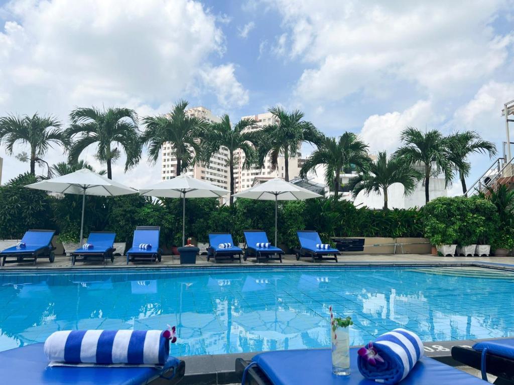 胡志明市Ramana Saigon Hotel的一个带蓝色椅子的游泳池,棕榈树