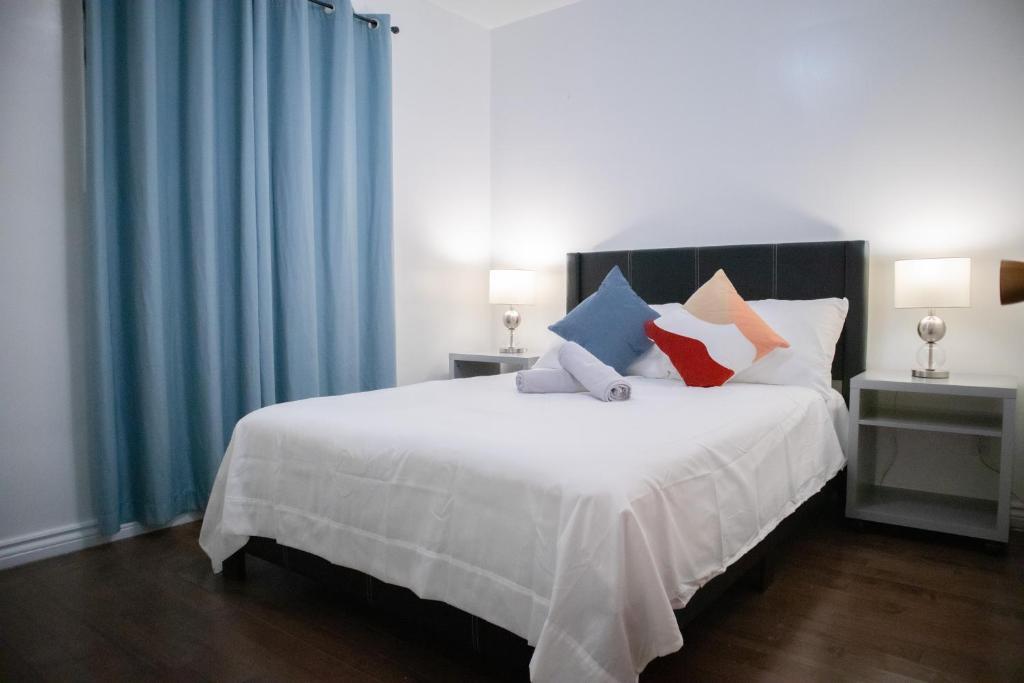 汉密尔顿Cozy Private Room-Your Perfect place in Hamilton的卧室配有一张带蓝色窗帘的大型白色床