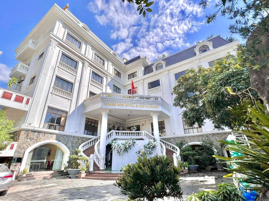 山萝Khách sạn Hoàng Sơn的一座白色的大建筑,前面有楼梯