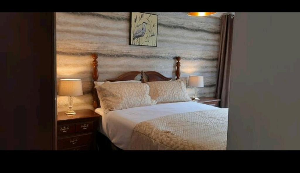 GreasbroughWingfield House 3 Bed的一间卧室配有一张床、两个床头柜和两盏灯。