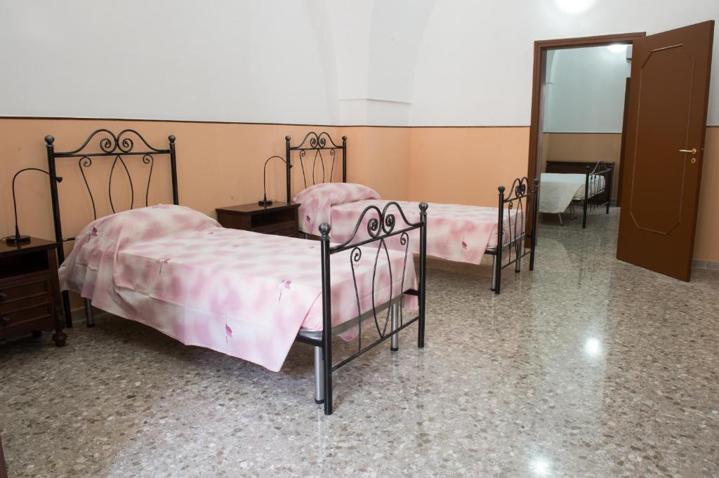 阿拉代奥B&b Pozzi Dolci的客房设有三张床、粉红色的床单和镜子