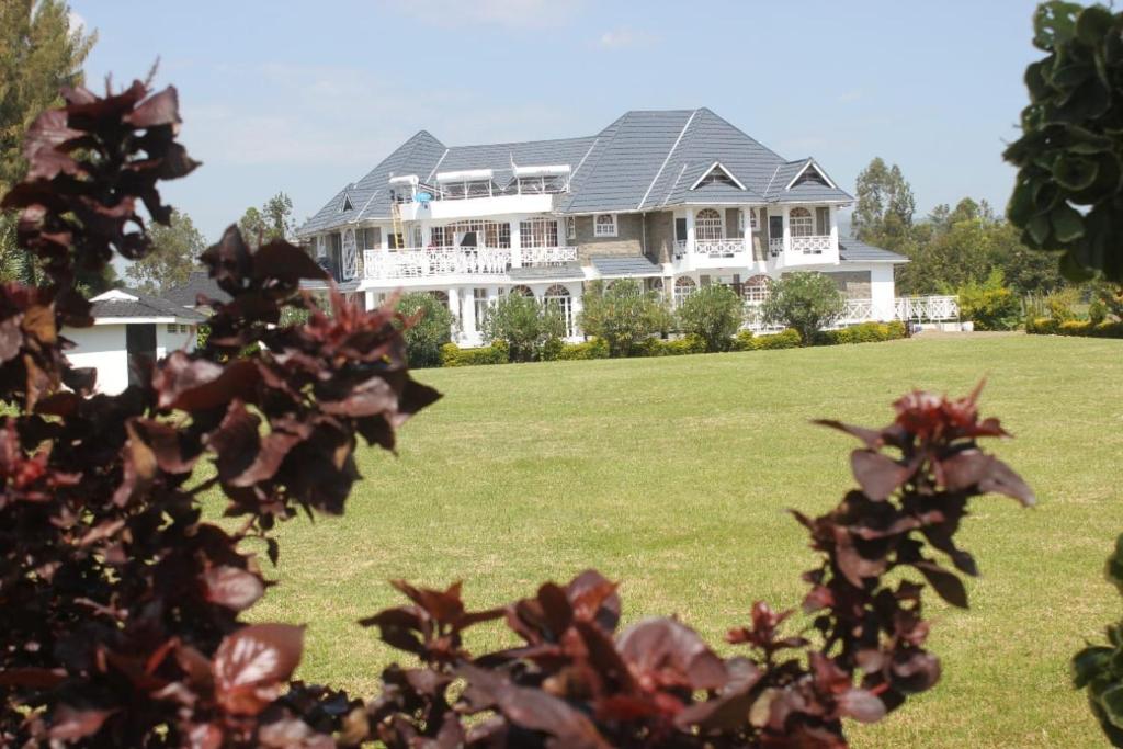 基苏木Balmoral Beach Hotel Kisumu的一座大型白色房子,设有大院子