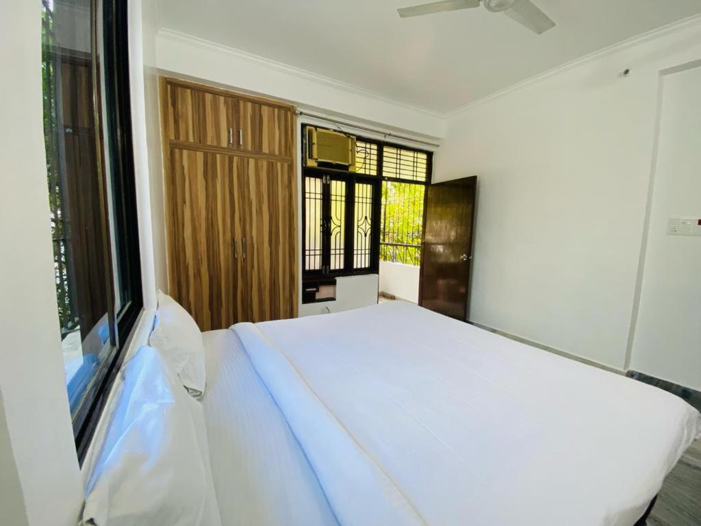 瓦拉纳西The white yard stays的卧室配有白色的床和窗户。