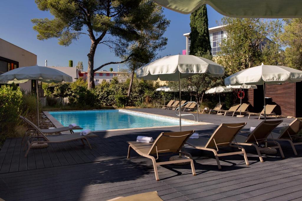 维特罗勒金色郁金香马赛机场酒店的游泳池旁设有躺椅和遮阳伞的游泳池