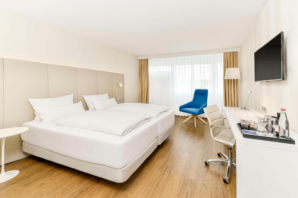 埃朗根埃朗根NH酒店的白色卧室配有一张白色大床和一张蓝色椅子