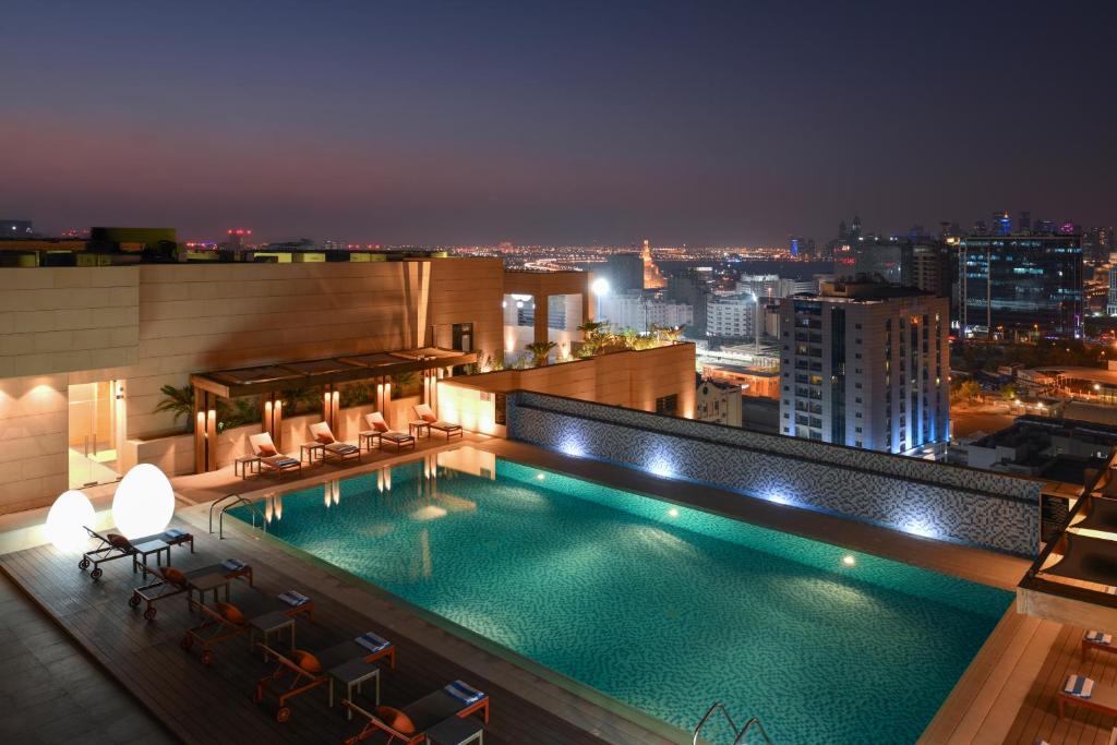 多哈Le Mirage Downtown的一座游泳池,在晚上在一座建筑的顶部