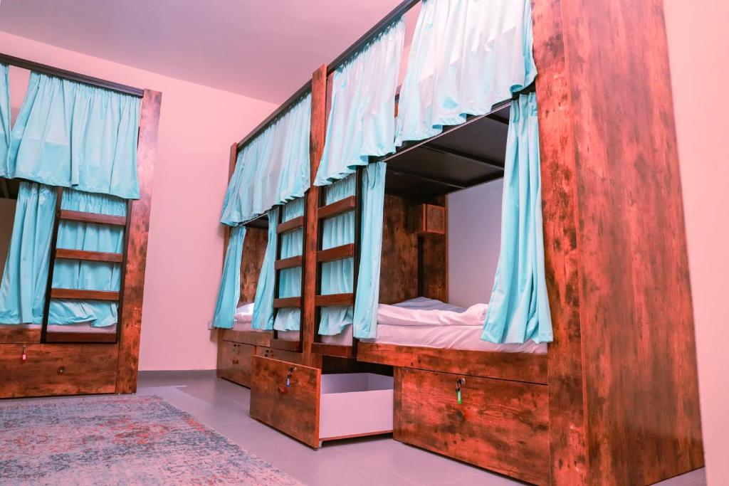阿布扎比The Villa Hostel Abu Dhabi的粉红色的客房配有两张双层床和蓝色窗帘