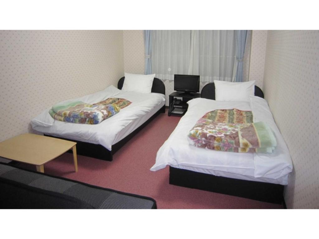 京都Pension Kitashirakawa - Vacation STAY 91700v的客房设有两张床、一张桌子和一张书桌。