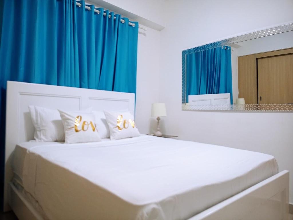 博卡奇卡Confortable apto. en Boca Chica的卧室配有一张带蓝色窗帘的大型白色床