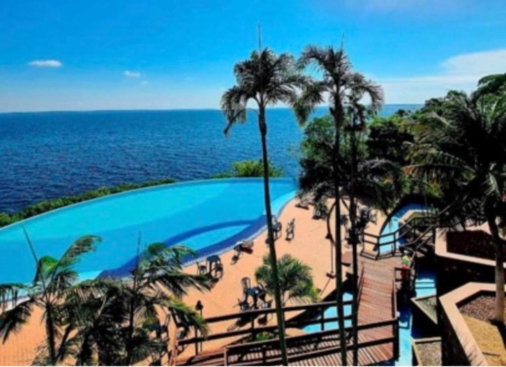 马瑙斯Hotel Tropical Executive Flat 918的享有棕榈树游泳池和大海的景色