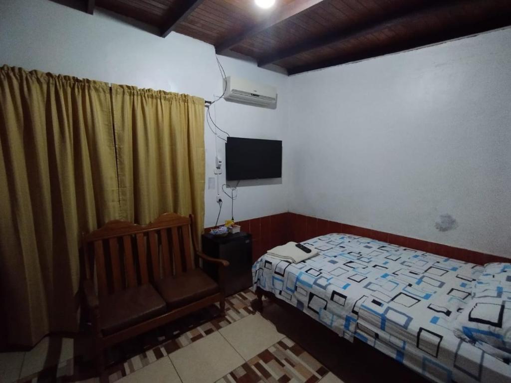 普卡尔帕LAS ORQUIDEAS Hospedaje的一间卧室配有一张床、一把椅子和电视