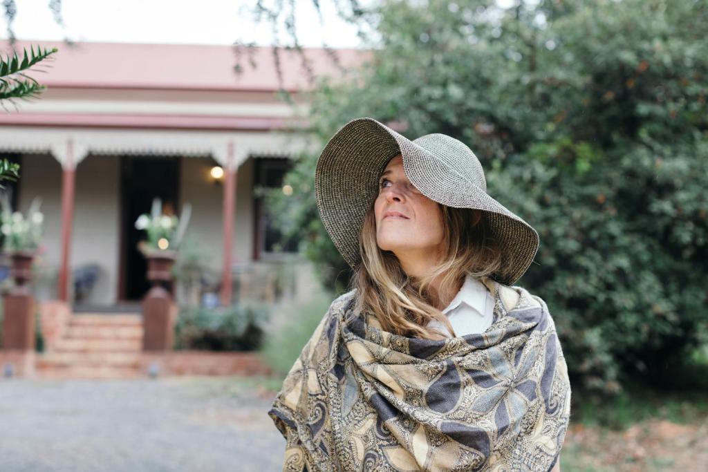 亚历山德拉Summerlands - Country Luxe的站在房子前面戴帽子的女人