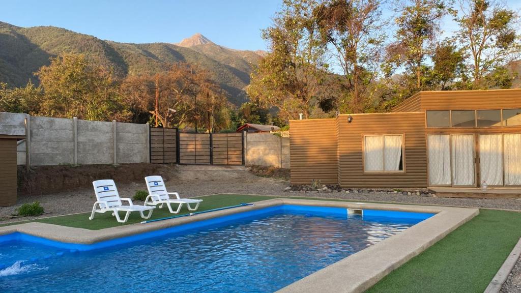 GranizoCabaña en Olmue con piscina compartida的一个带两把椅子的游泳池以及一座房子