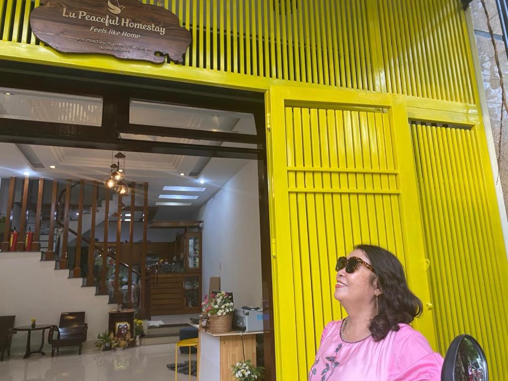 岘港Lu Peaceful Homestay的站在黄色墙前的女人