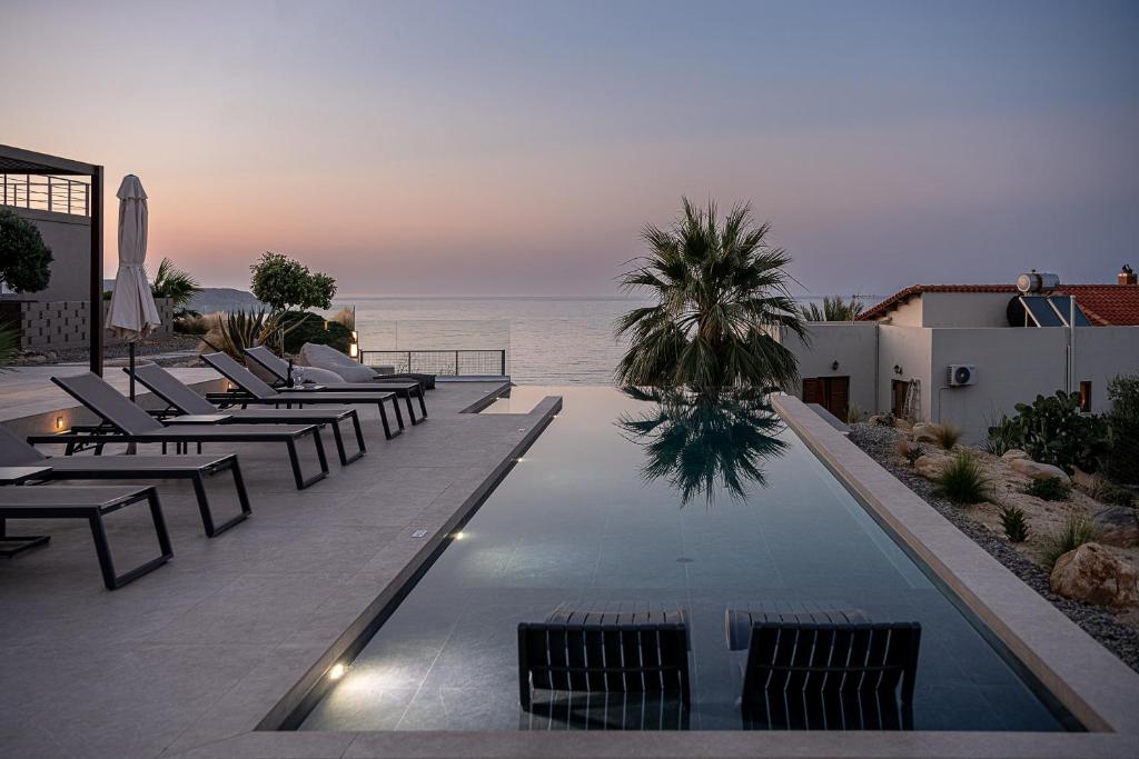 干尼亚AGAVE HILL LUXURY HOUSE的一个带椅子的游泳池,背景是大海