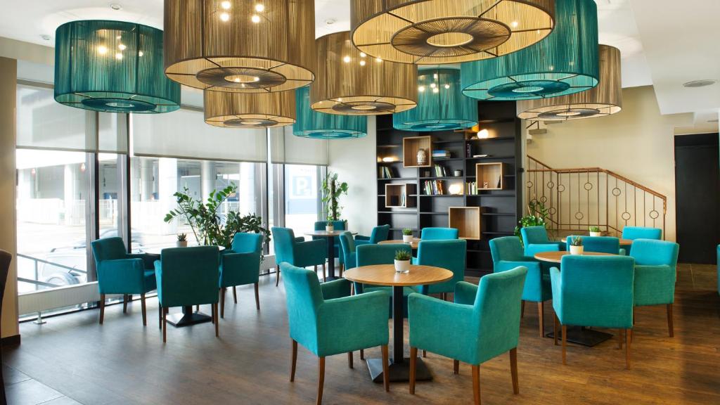 塔林Hestia Hotel Seaport Tallinn的餐厅设有蓝色的桌椅和吊灯。
