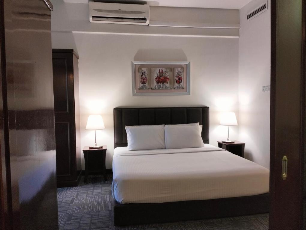 吉隆坡Luxy Service Apartment at Times Square KL的一间卧室配有一张带白色床单和两盏灯的床。