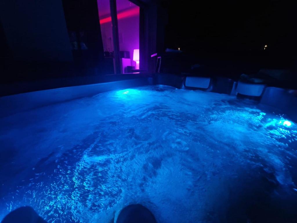 加龙河畔波泰Studio naturiste jacuzzi的蓝色和粉红色灯的房间内的热水浴缸